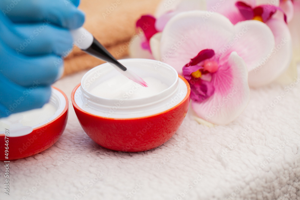 Cosmetologist mixing moisturizing mask with brush to apply on young womans face Cosmetologist mixing moisturizing mask with brush to apply on young womans face