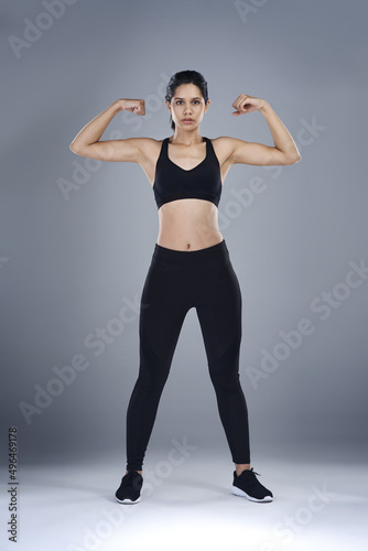 Inner strength is the greatest form of strength to have. Full length shot of a sporty young woman flexing her biceps against a grey background.