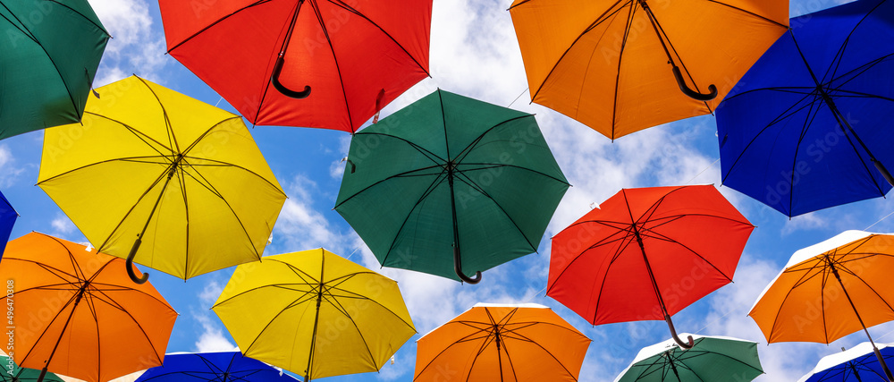 colorful umbrellas hanging against blue sky background. banner