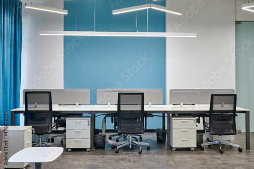 Empty office desk with vacant workplaces in blue interior design