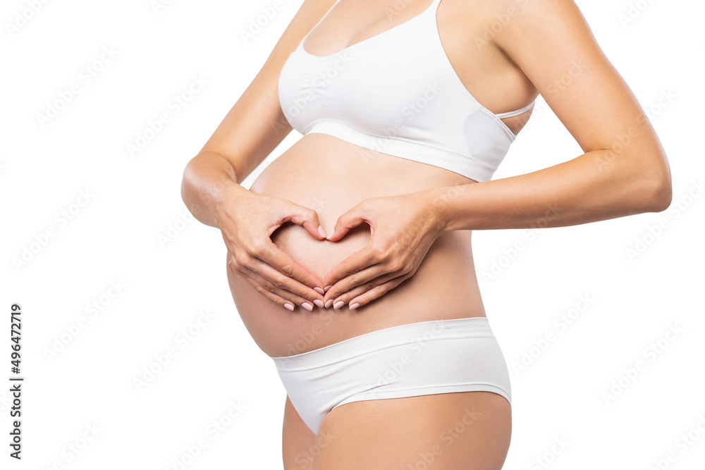 Young pregnant woman in swimsuit. Girl expecting a baby and touching her belly isolated on white background. Close-up image. Young pregnant woman in swimsuit. Girl expecting a baby and touching her belly isolated on white background. Close-up image.
