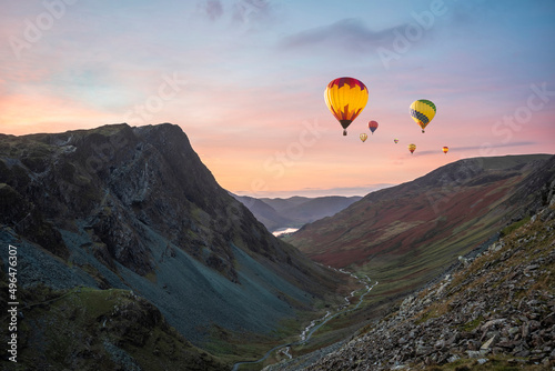 Digital composite image of hot air balloons over Stunning colorful landscape image of view down Honister Pass to Buttermere from Dale Head in Lake District during Autumn sunset