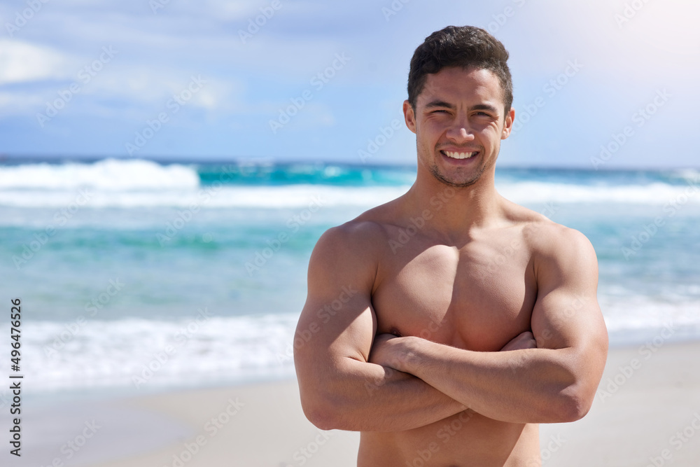 Proud of how far Ive come. Portrait of a handsome young man standing with his arms folded on the beach.