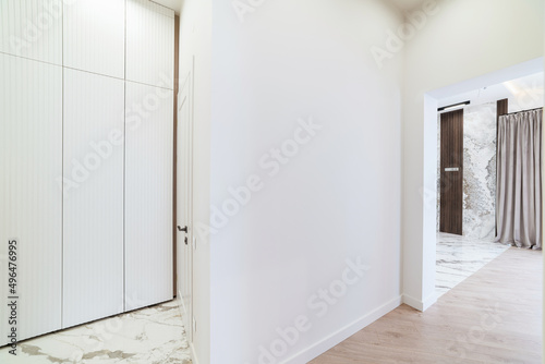 white corridor in the interior of the house with a white closet and a dark floor