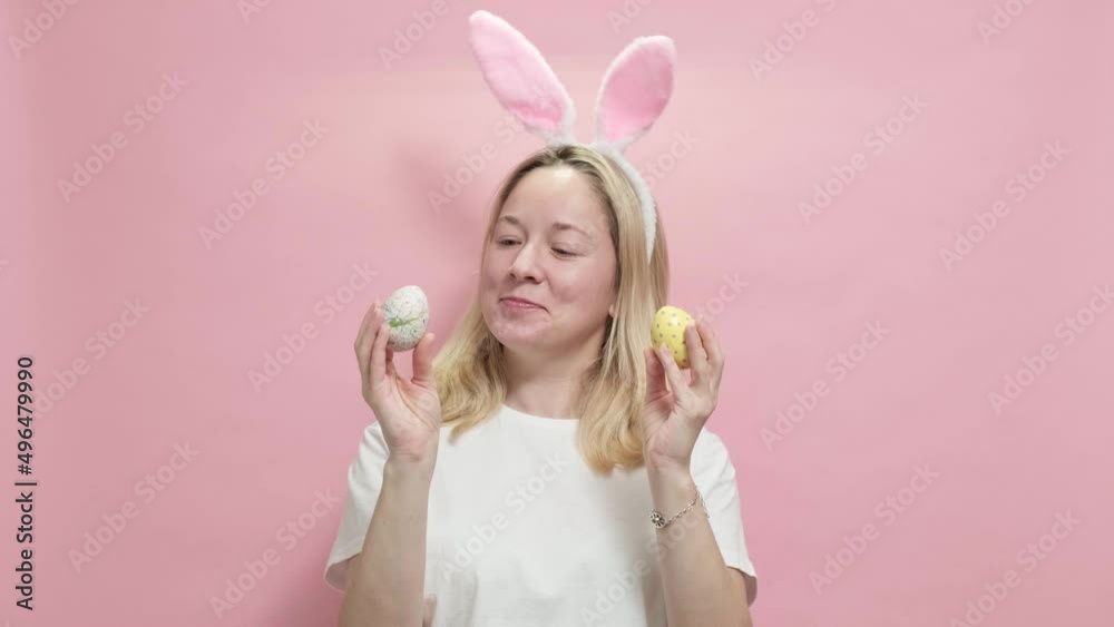 4k. Happy easter. Beautiful girl in Easter bunny ears holding painted easter eggs on pink background going to celebrate Easter, stands over pink studio background. Spring holiday concept 4k. Happy easter. Beautiful girl in Easter bunny ears holding painted easter eggs on pink background going to celebrate Easter, stands over pink studio background. Spring holiday concept