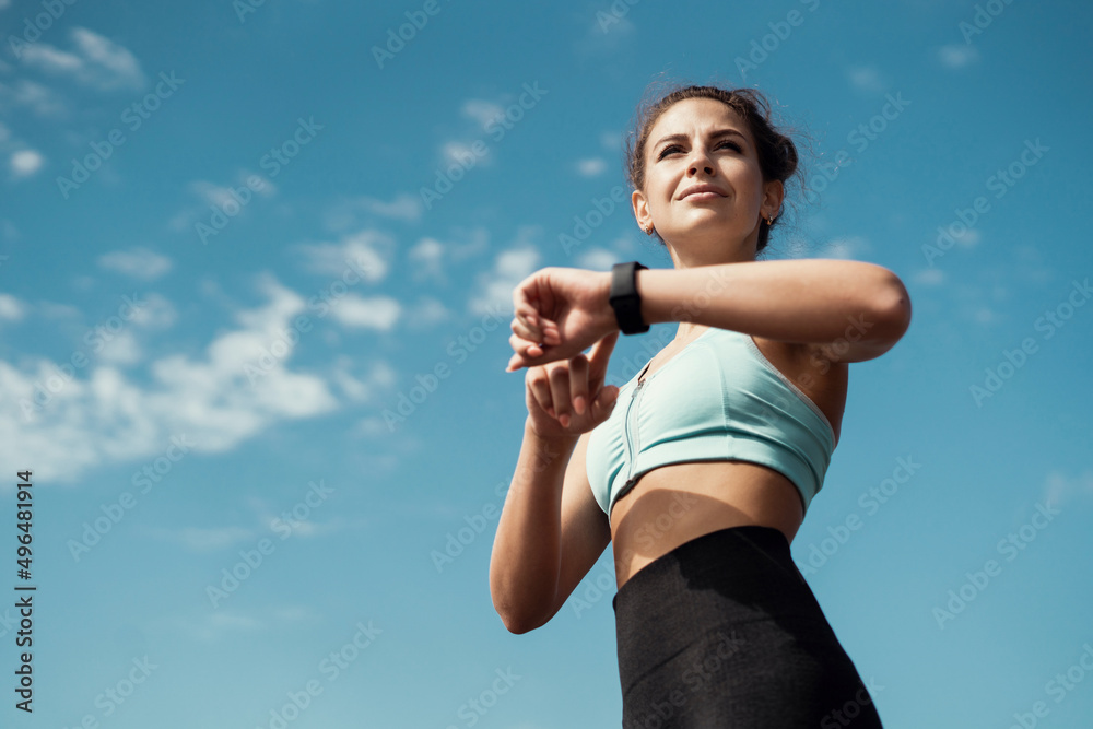 Uses a smart watch athletic confident woman active outdoor training, running and body warm-up Uses a smart watch athletic confident woman active outdoor training, running and body warm-up