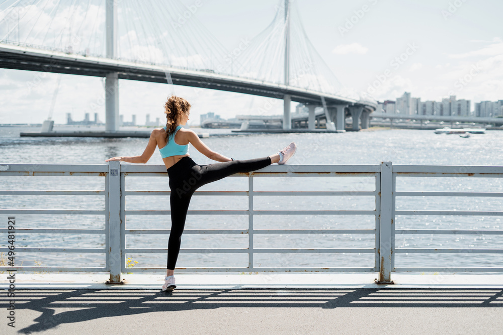 Athletic confident woman active outdoor training, stretching and warming up the body, sportswear