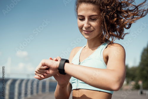 Uses a smart watch athletic confident woman active outdoor training, running and body warm-up