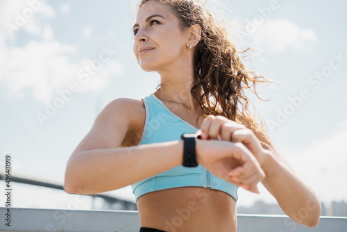Uses a pulse smartwatch athletic confident woman active outdoor training, running and body warm-up
