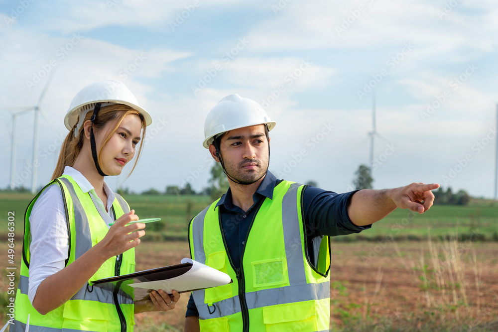 Two Asian engineers team working in wind turbine farm. Two Asian engineers team working in wind turbine farm.