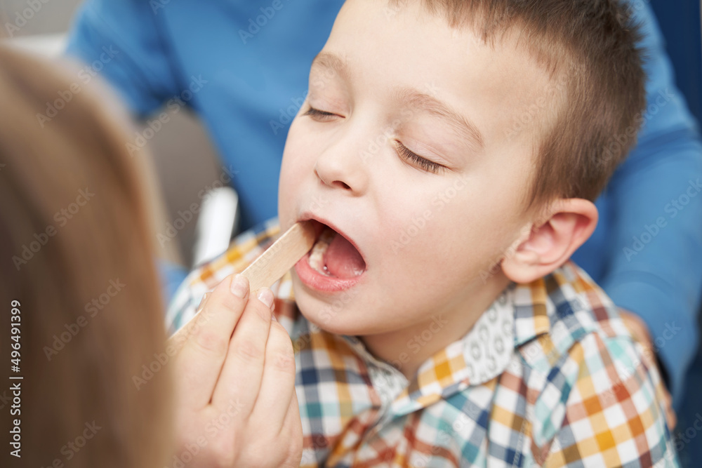 Doctor checking child throat with tongue depressor Doctor checking child throat with tongue depressor