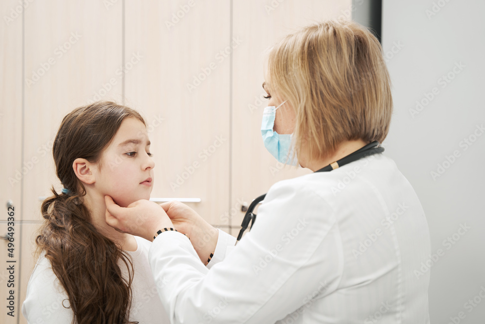 Female pediatrician examining child lymph nodes in clinic Female pediatrician examining child lymph nodes in clinic