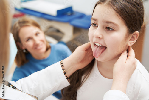 Doctor examining child lymph nodes and mouth in clinic