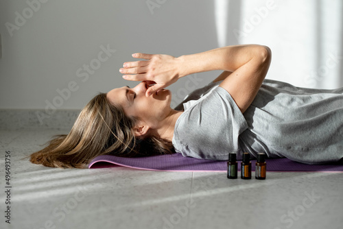 woman meditates with essential oils while lying on a yoga mat. Ultrasonic and humidifying aromatherapy. Meditation fitness and exercise concept copy space. Active lifestyle. home or gym club photo
