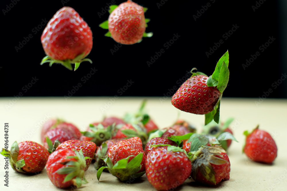 Fresh strawberries floating above the table against a studio black background Fresh strawberries floating above the table against a studio black background