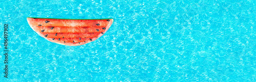 Banner of red watermelon (air mattress) floating on the water surface in the blue fresh pool. Top view, flat lay, copy space. Vacation, happy childhood concept..