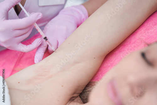 Experienced dermatologist treating young woman for hyperhidrosis
