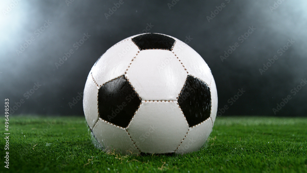 Soccer ball on grass with dark background and lights