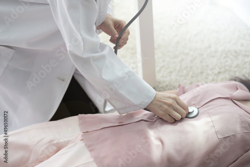 Doctor examining woman's stomach with stethoscope