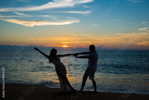 Silhouette of hot dancing couple at golden tropical sea sunset background.
