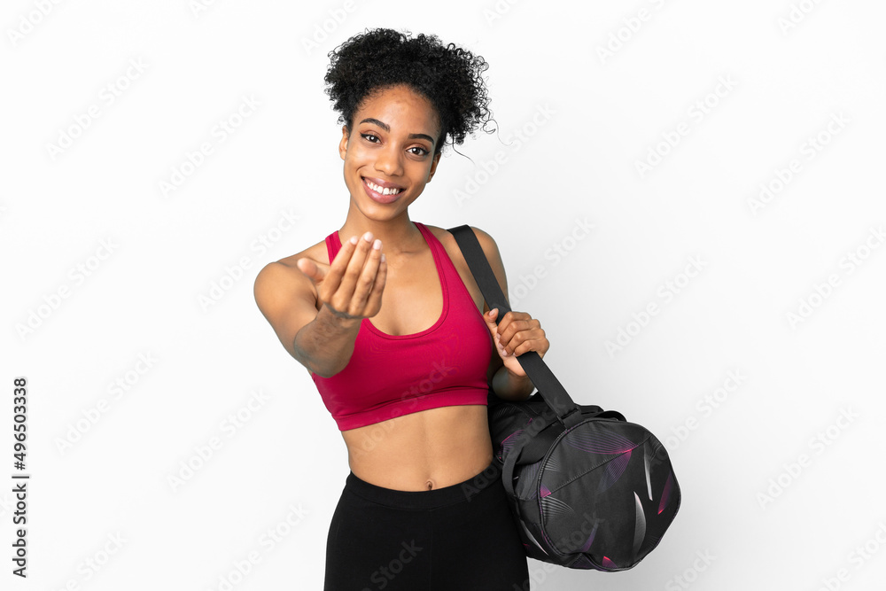 Young sport african american woman with sport bag isolated on blue background inviting to come with hand. Happy that you came
