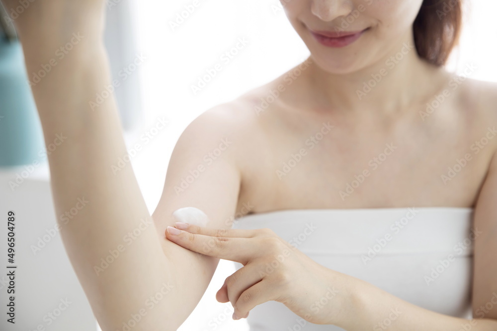 Naklejka premium Young woman applying moisturizer on arm
