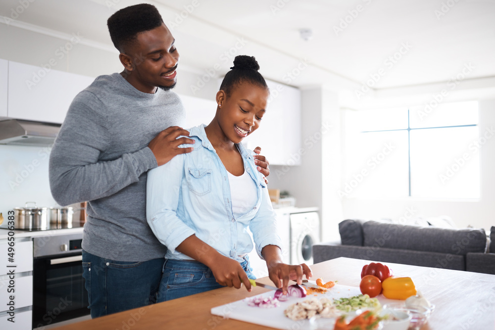 Do you need any help. Shot of a man embracing his wife from behind while shes with chopping vegetables. Do you need any help. Shot of a man embracing his wife from behind while shes with chopping vegetables.