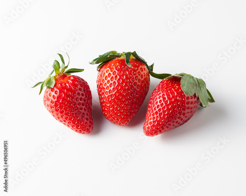 Three strawberries are on the table. On a white background.
