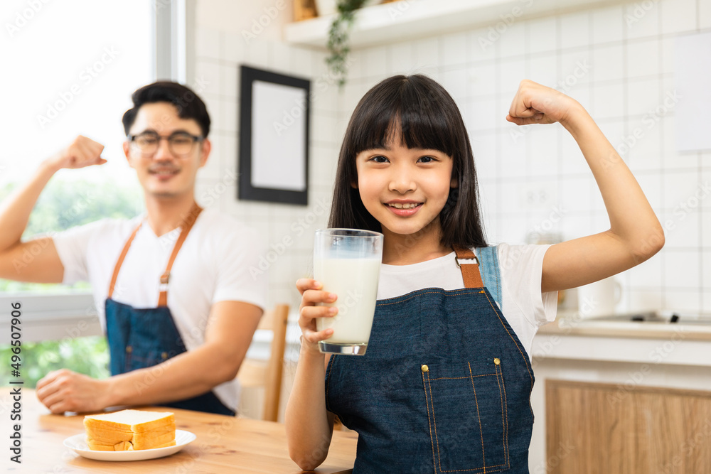 Asian family enjoying breakfast at cozy kitchen, little girl daughter sitting on table, drinking milk with smiling father and mother in morning. Happy family in kitchen. Asian family enjoying breakfast at cozy kitchen, little girl daughter sitting on table, drinking milk with smiling father and mother in morning. Happy family in kitchen.