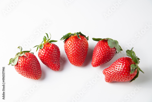 Five Strawberries are on the table. On a white background.