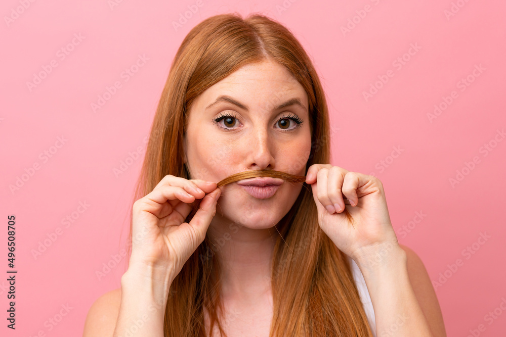 Young redhead woman isolated on pink background touching her hair. Close up portrait Young redhead woman isolated on pink background touching her hair. Close up portrait