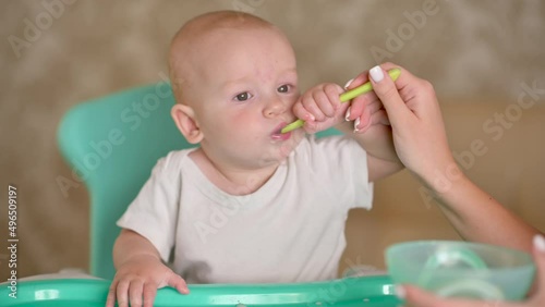 Children food. mother gives baby food from a baby spoon. Little kid eats puree with a spoon. Loving mother takes care of the child
