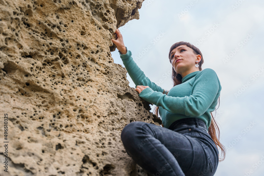 Fototapeta premium Woman climbing rocks with determination and looking into the distance