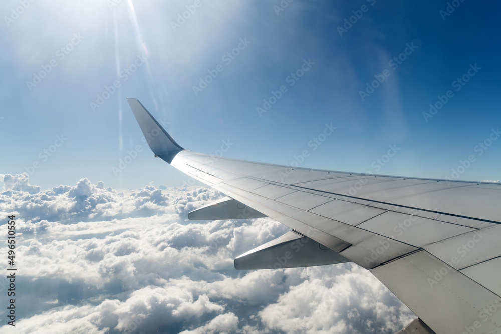 Obraz premium Wing of airplane flying above clouds