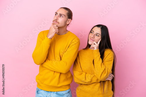 Young caucasian couple isolated on pink background thinking an idea while looking up © luismolinero