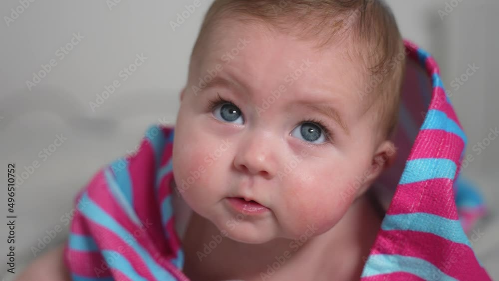 Cute portrait of a cheerful chubby baby toddler girl in striped bathrobe with hoodie smiling face-down on the bed. Cute portrait of a cheerful chubby baby toddler girl in striped bathrobe with hoodie smiling face-down on the bed.