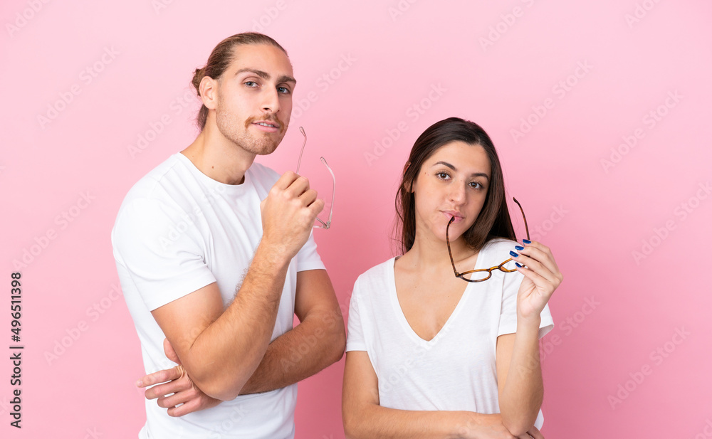 Young caucasian couple isolated on pink background With glasses with happy expression Young caucasian couple isolated on pink background With glasses with happy expression