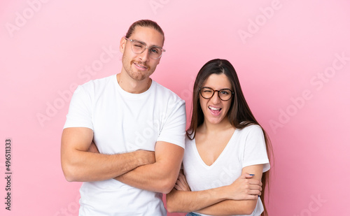 Young caucasian couple isolated on pink background With glasses and happy expression