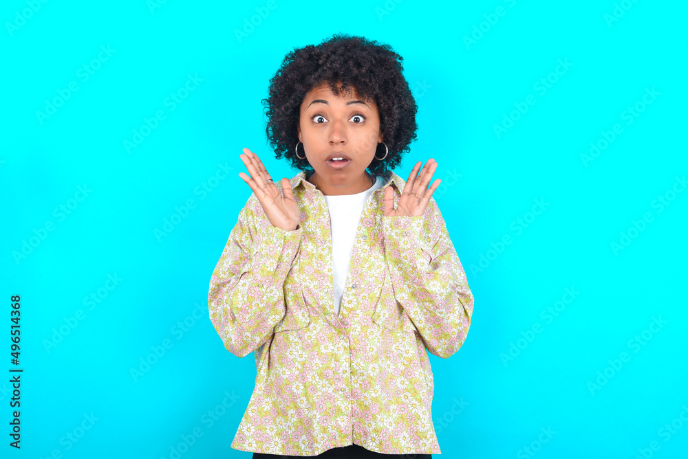 © Roquillo - Surprised terrified young girl with afro hairstyle wearing floral shirt over blue background Gestures with uncertainty, stares at camera, puzzled as doesn't know answer on tricky question, © Roquillo - Surprised terrified young girl with afro hairstyle wearing floral shirt over blue background Gestures with uncertainty, stares at camera, puzzled as doesn't know answer on tricky question,