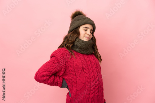 Little girl with winter hat isolated on pink background suffering from backache for having made an effort © luismolinero
