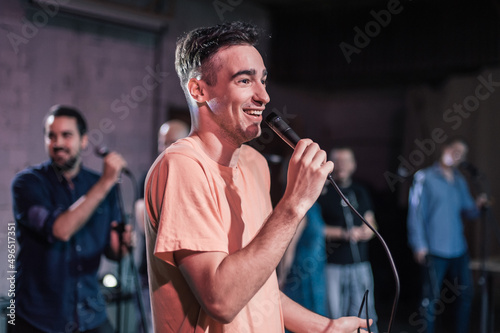 Smiling and witty stand up actor comedian on stage, talking and singing