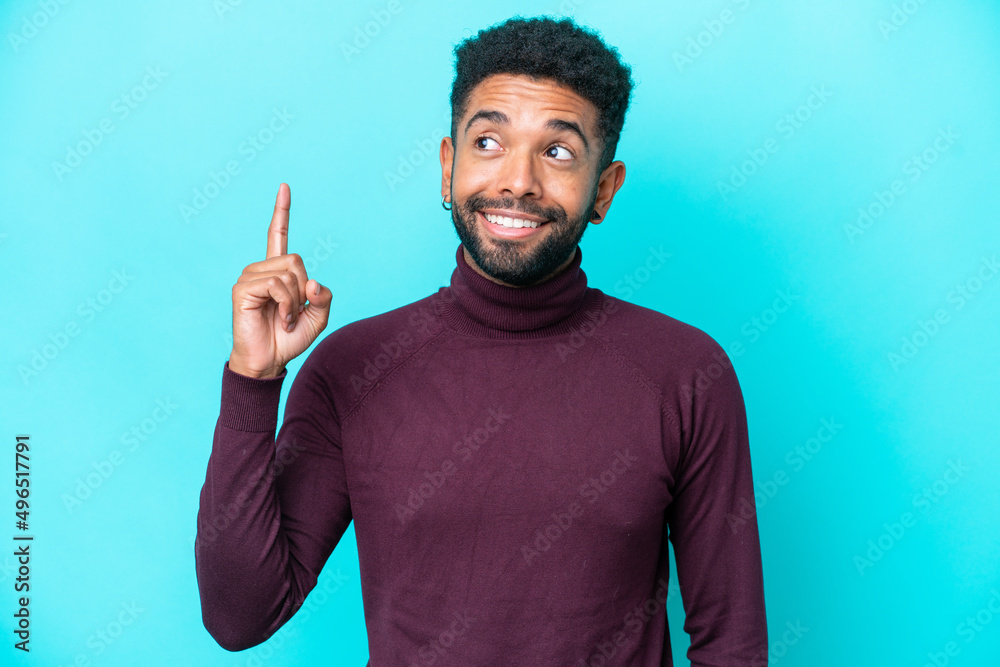 Fototapeta premium Young Brazilian man isolated on blue background thinking an idea pointing the finger up