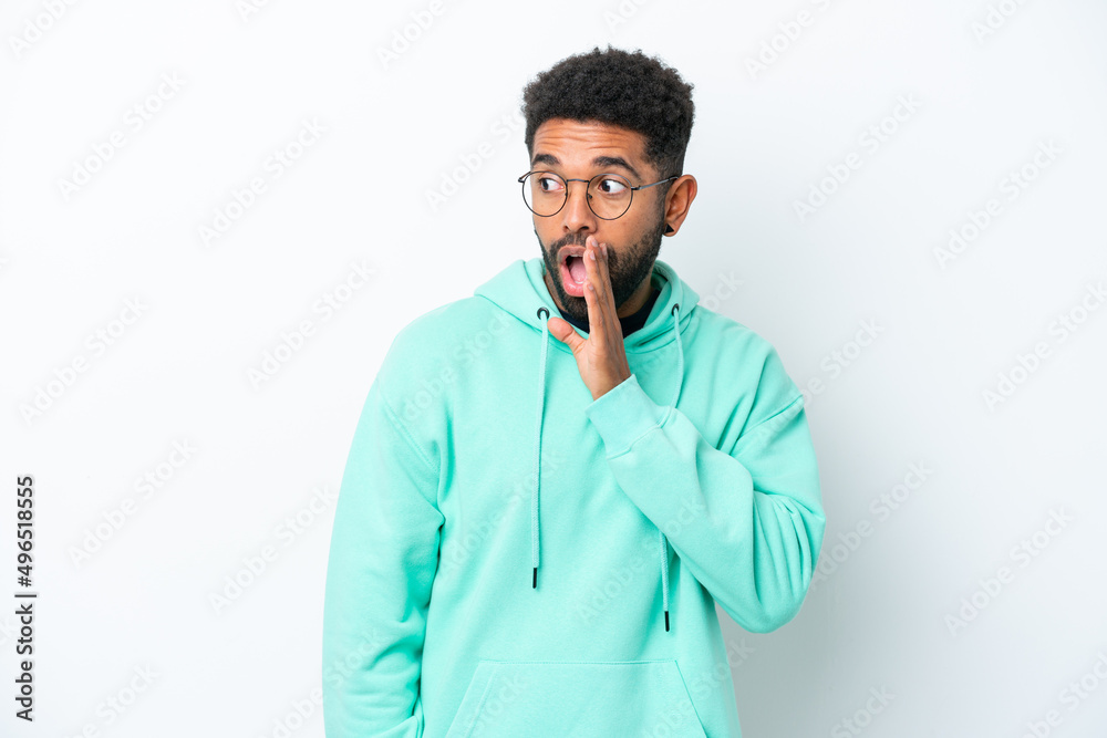 Young Brazilian man isolated on white background whispering something with surprise gesture while looking to the side Young Brazilian man isolated on white background whispering something with surprise gesture while looking to the side