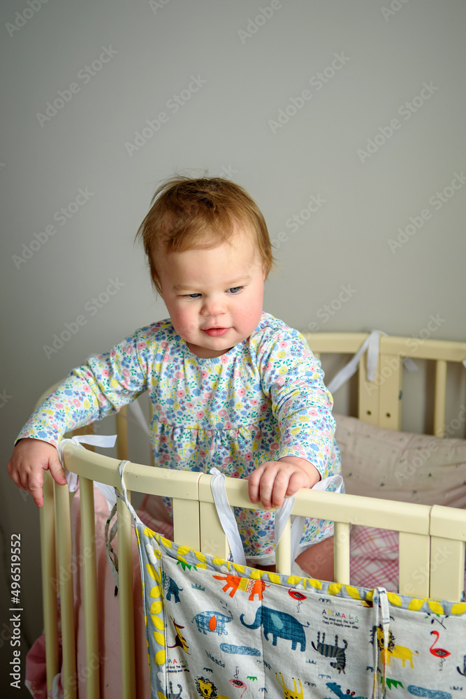 Cute girl of ten months old, playing alone in a crib at home in the afternoon or in the morning. Cute girl of ten months old, playing alone in a crib at home in the afternoon or in the morning.