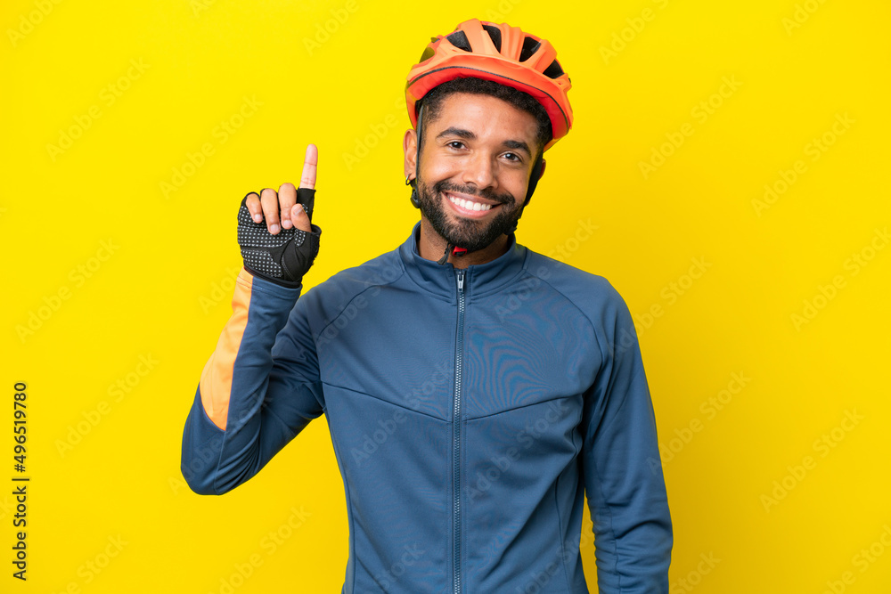 Young cyclist Brazilian man isolated on yellow background pointing up a great idea
