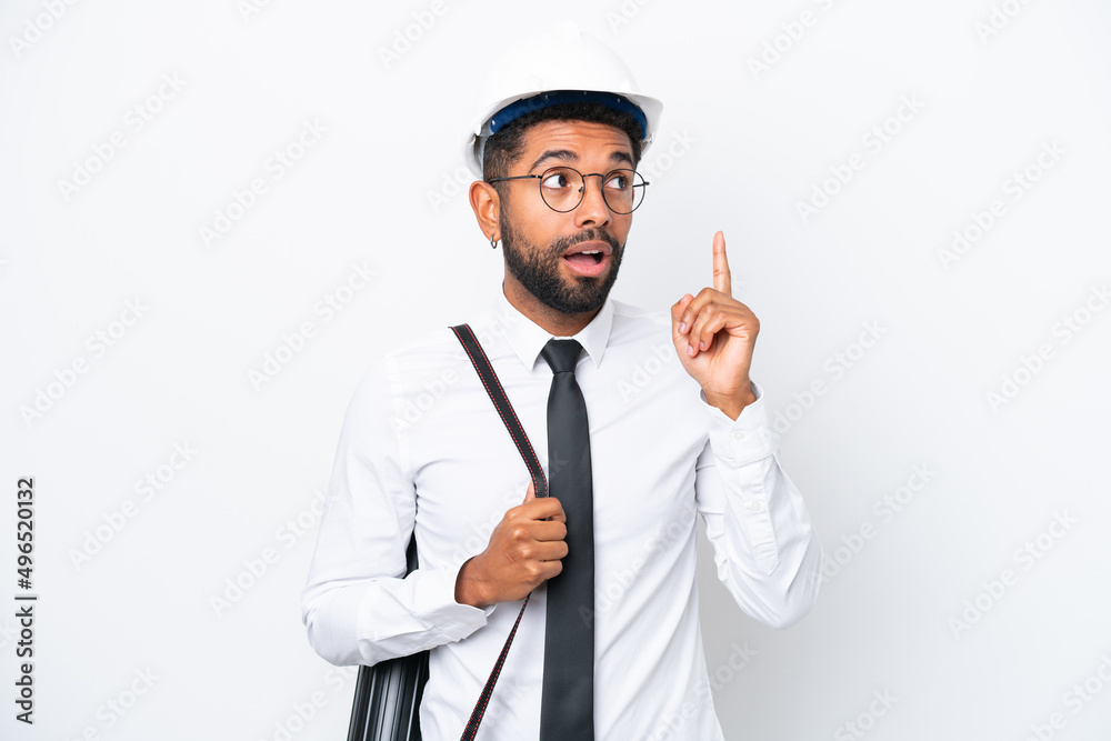 Young architect Brazilian man with helmet and holding blueprints isolated on white background thinking an idea pointing the finger up Young architect Brazilian man with helmet and holding blueprints isolated on white background thinking an idea pointing the finger up