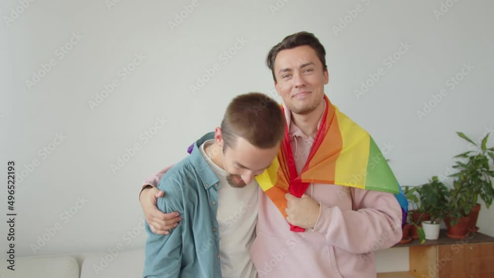 Two handsome young men are showing lgbt flag, smiling and hugging Two handsome young men are showing lgbt flag, smiling and hugging