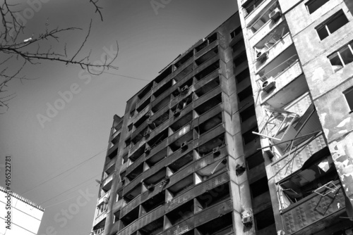 A destroyed high-rise building with people in Kharkov after the shelling of Russian troops. War of Russia against Ukraine. Black and white photo of the war.