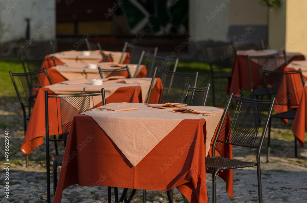 tables of an open-air restaurant in the square of a tourist place, a table well prepared with colored tablecloths, on holidays and holidays most tourists love to dine outdoors in the summer. tables of an open-air restaurant in the square of a tourist place, a table well prepared with colored tablecloths, on holidays and holidays most tourists love to dine outdoors in the summer.