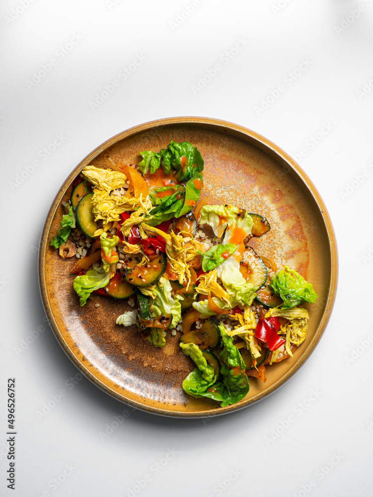 Cesar Salad with quinoa , chicken, cucumbers, pepper, sesam, kimchi. On a ceramic plate, with a white background Cesar Salad with quinoa , chicken, cucumbers, pepper, sesam, kimchi. On a ceramic plate, with a white background